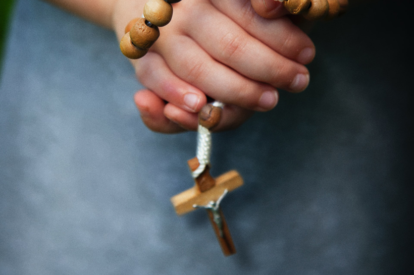 Manos de una nena sosteniendo un rosario