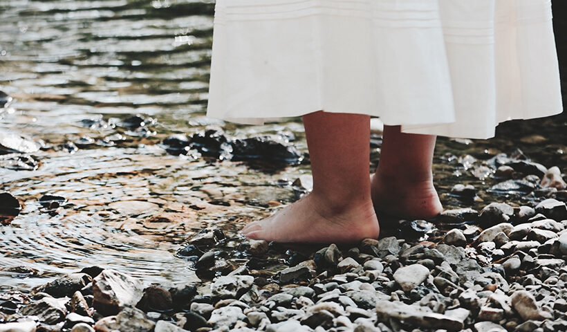 Pies descalzos de una niña a la orilla de una laguna