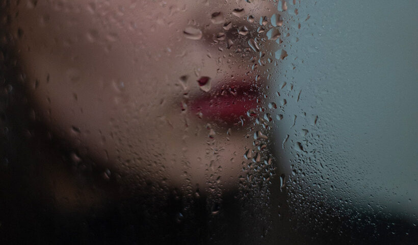 Rostro de mujer detrás de un vidrio mojado
