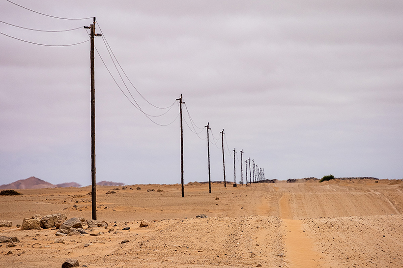 Línea de postes que se pierden en el horizonte de un desierto