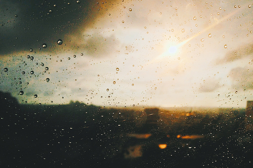 El cielo y el sol detrás de un vidrio con gotas.
